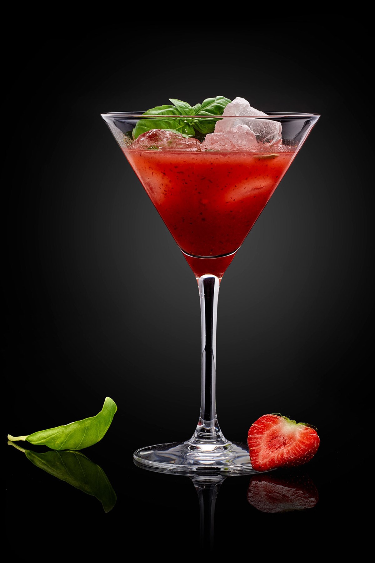 Cocktail rouge à la fraise et au basilic sur fond noir.