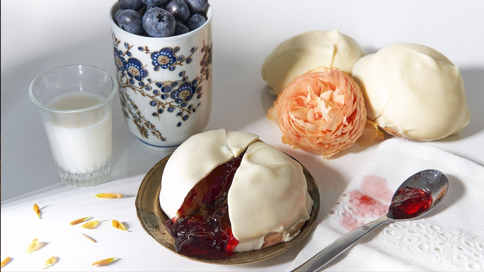 Dessert blanc à la meringue et coulis rouge, accompagné de myrtilles, lait et fleurs.