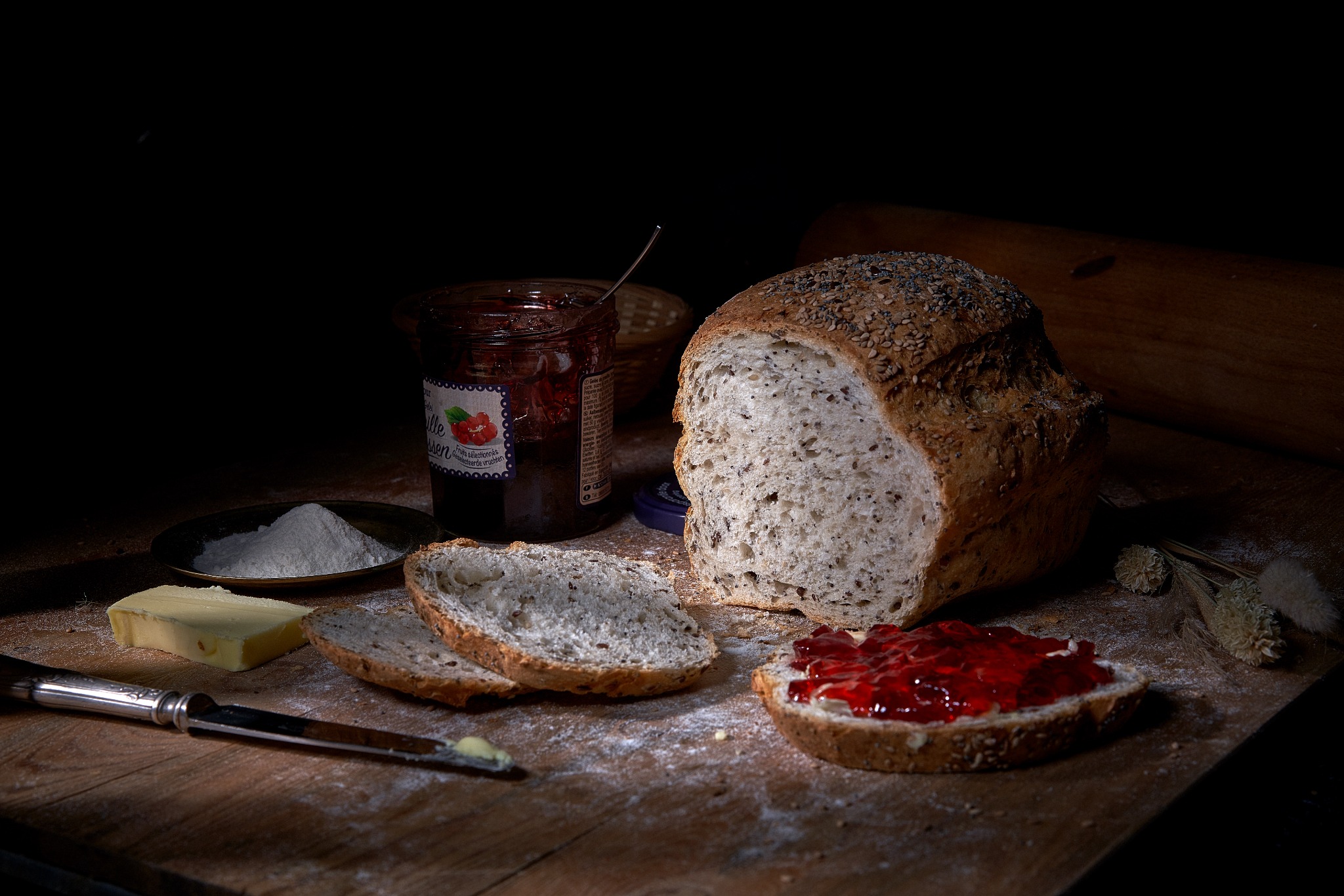 Pain artisanal et confiture sur une table en bois.